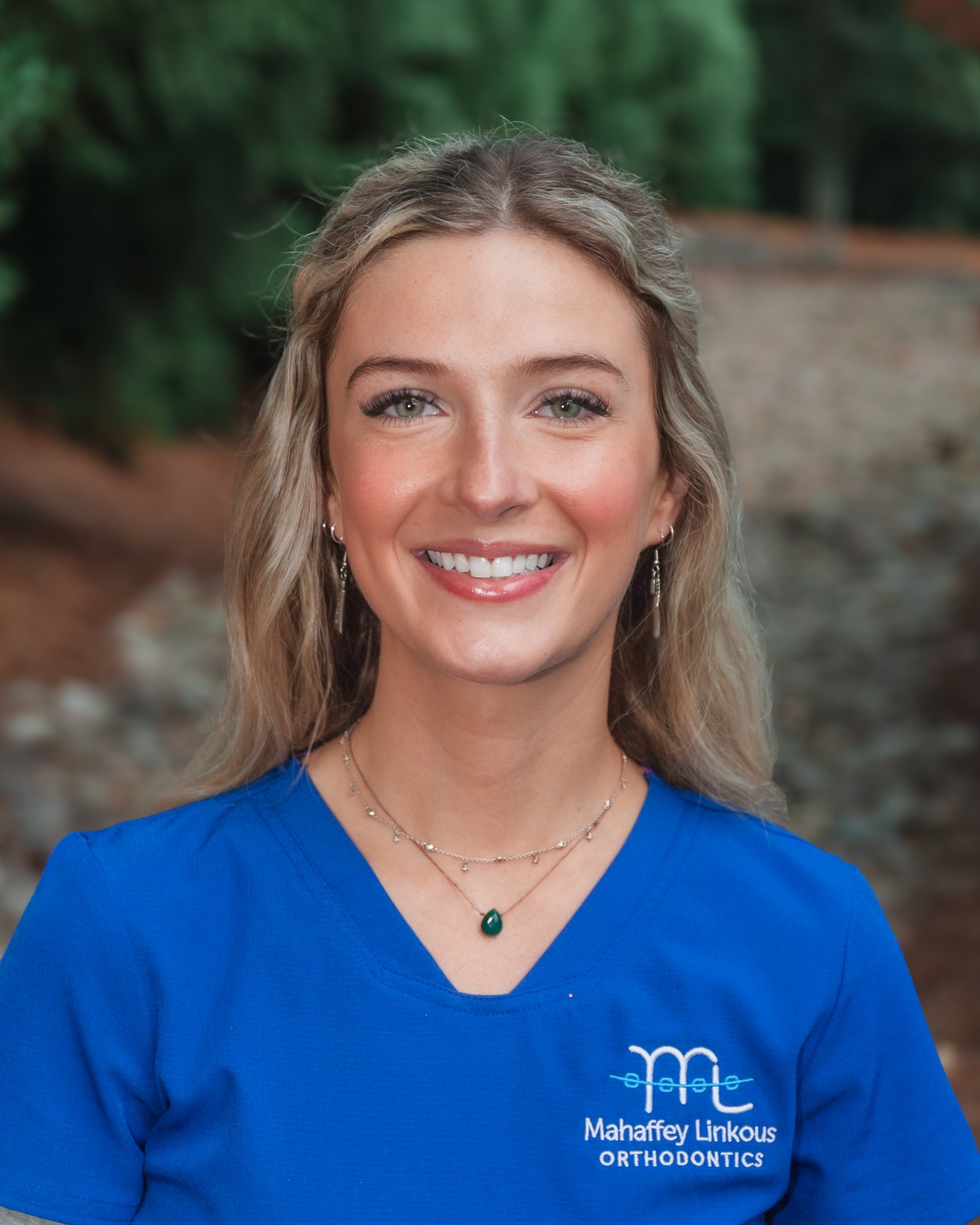 Bri, Clinical Assistant at Mahaffey Linkous Orthodontics, smiling outdoors in a branded blue polo