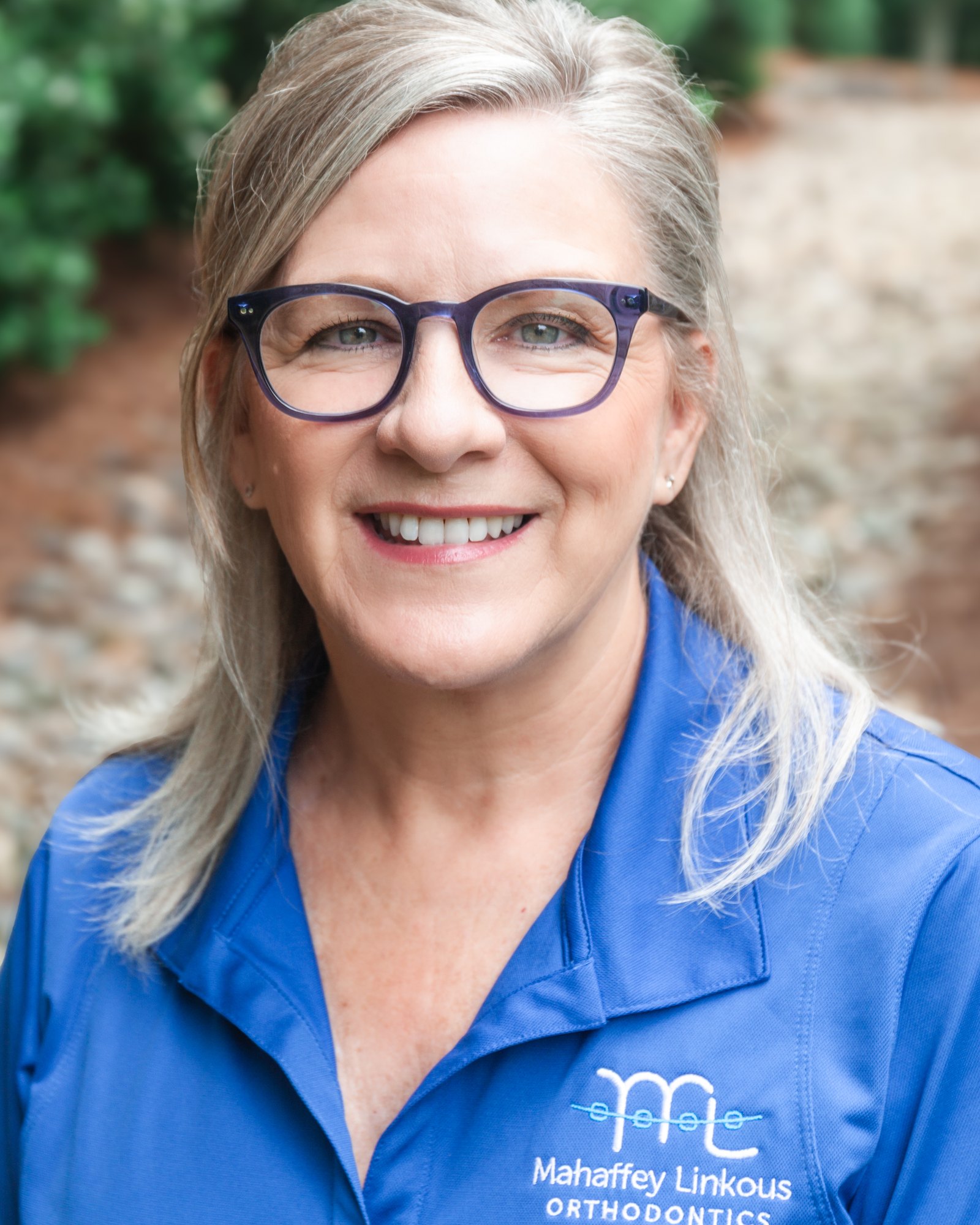 Christine, Treatment Coordinator at Mahaffey Linkous Orthodontics, smiling outdoors in a branded blue polo