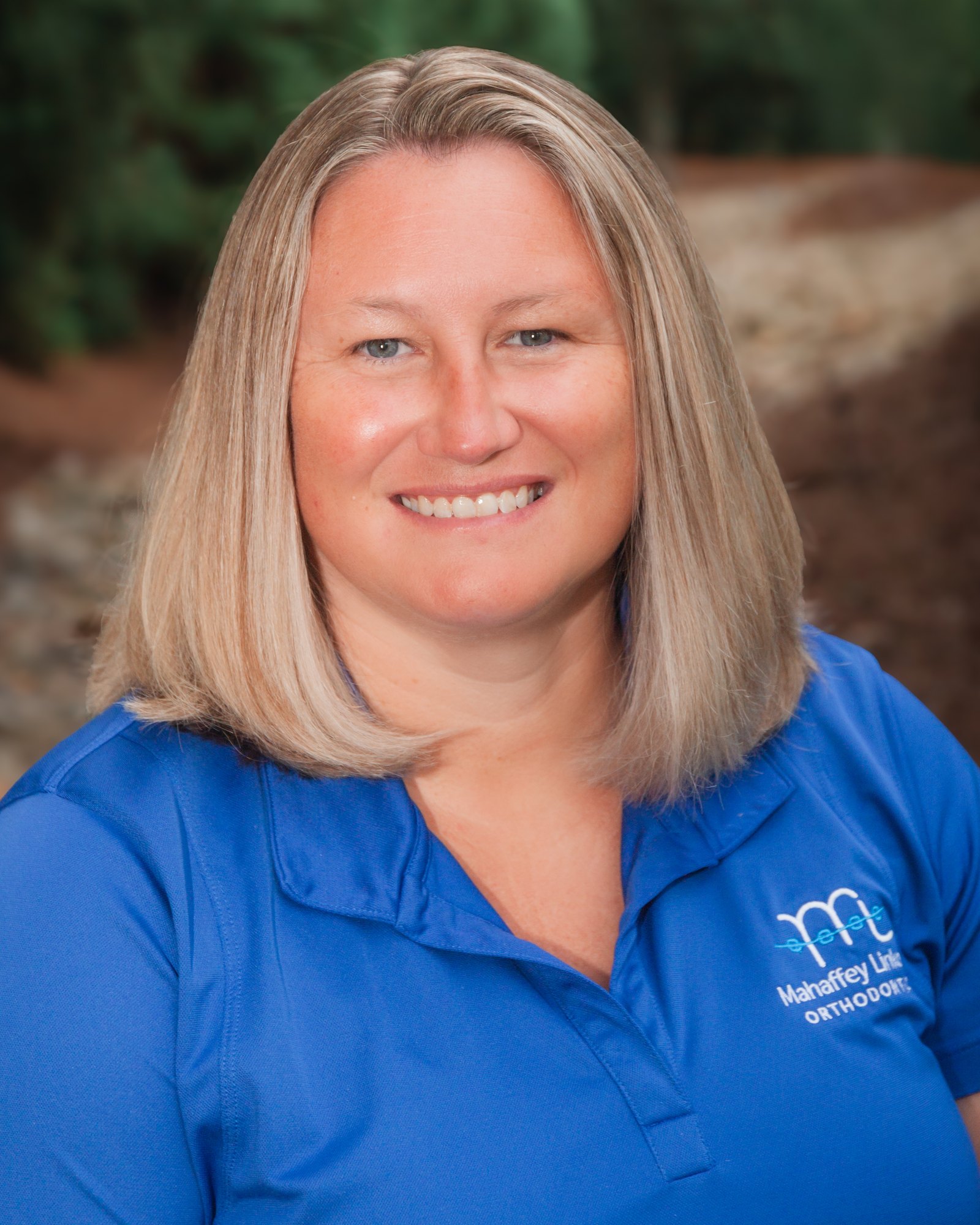 Heather, Operations Manager at Mahaffey Linkous Orthodontics, smiling outdoors in a branded blue polo