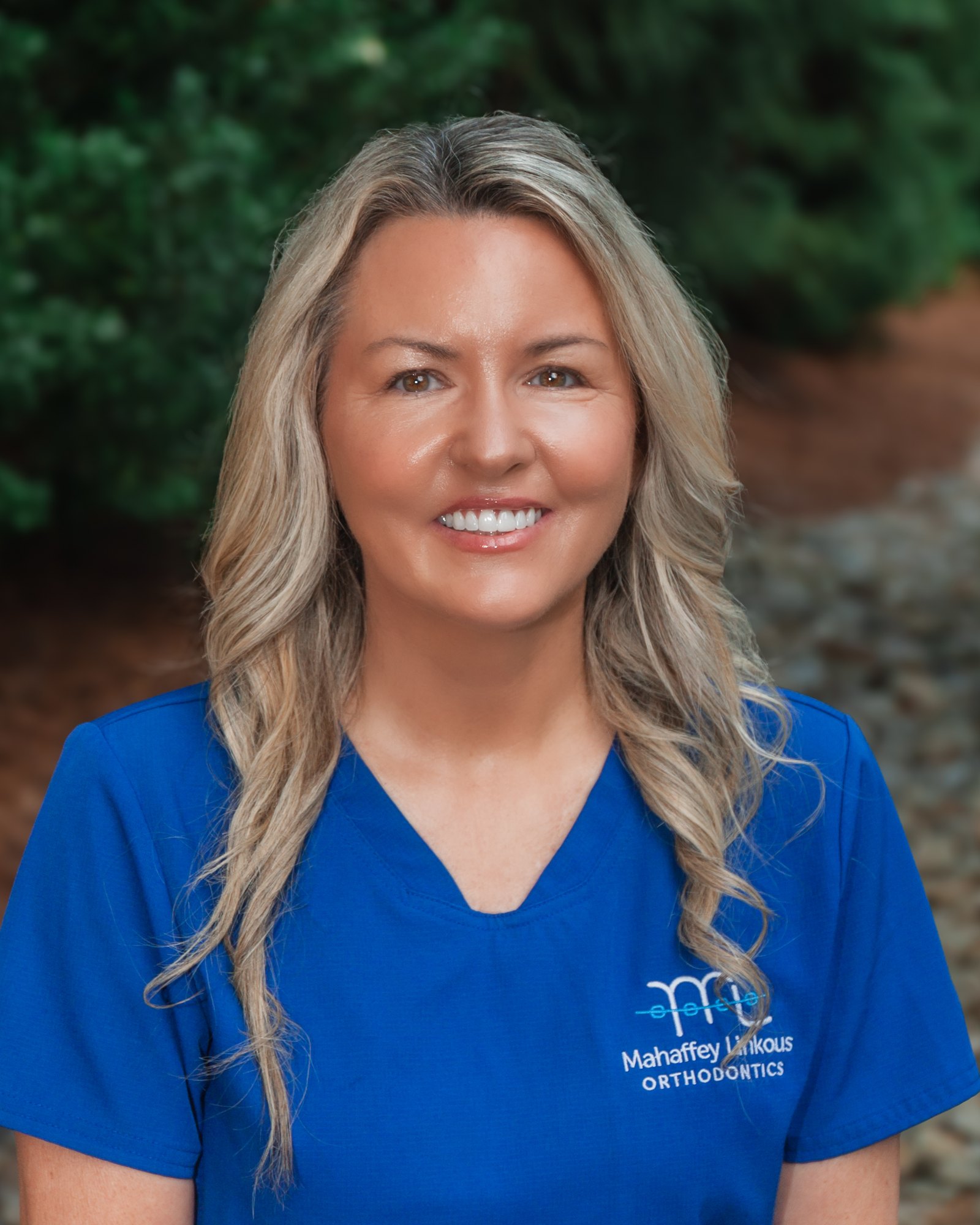 Jenn, Clinical Assistant at Mahaffey Linkous Orthodontics, smiling outdoors in a branded blue polo
