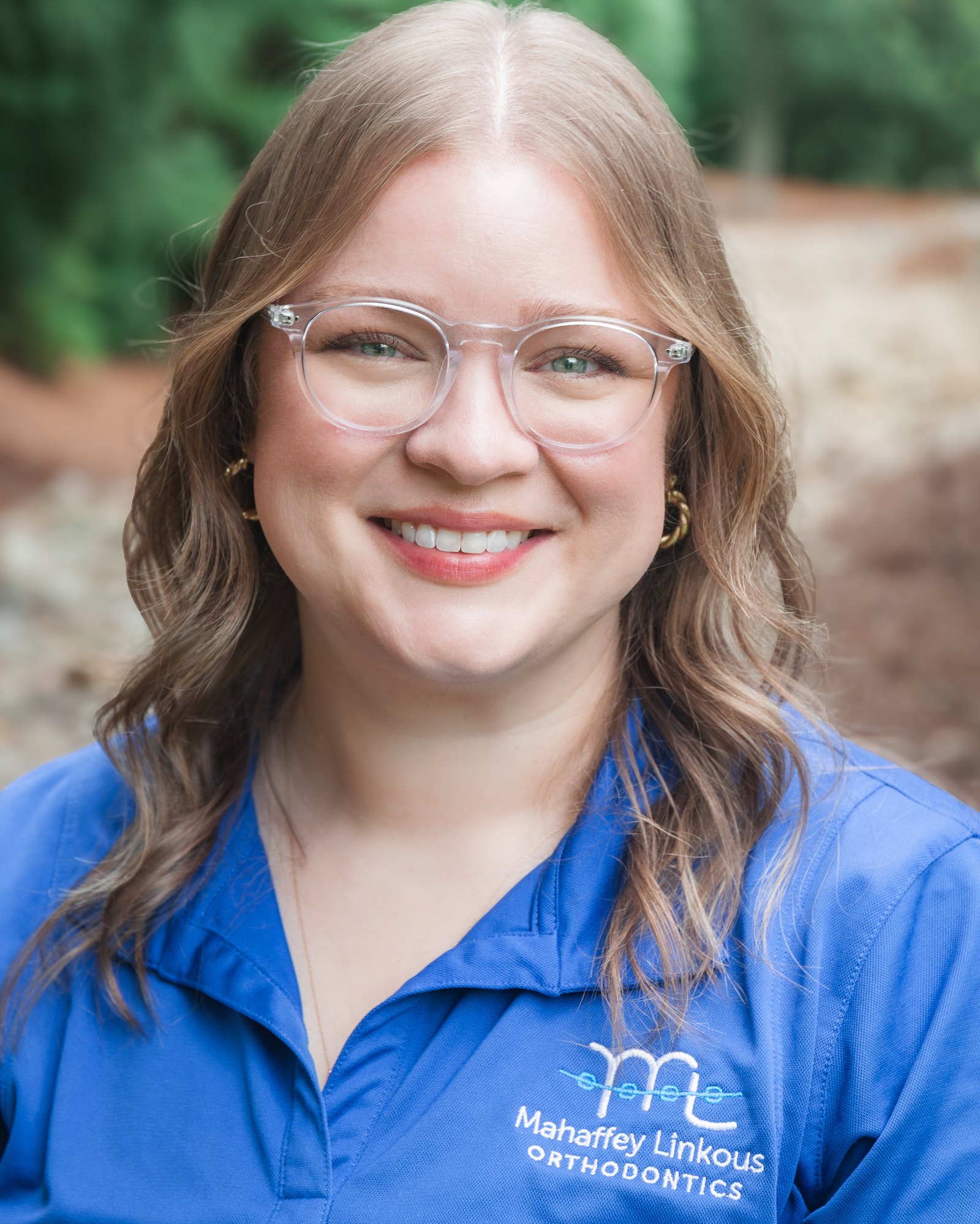 Rachel, Scheduling Coordinator at Mahaffey Linkous Orthodontics, smiling outdoors in a branded blue polo