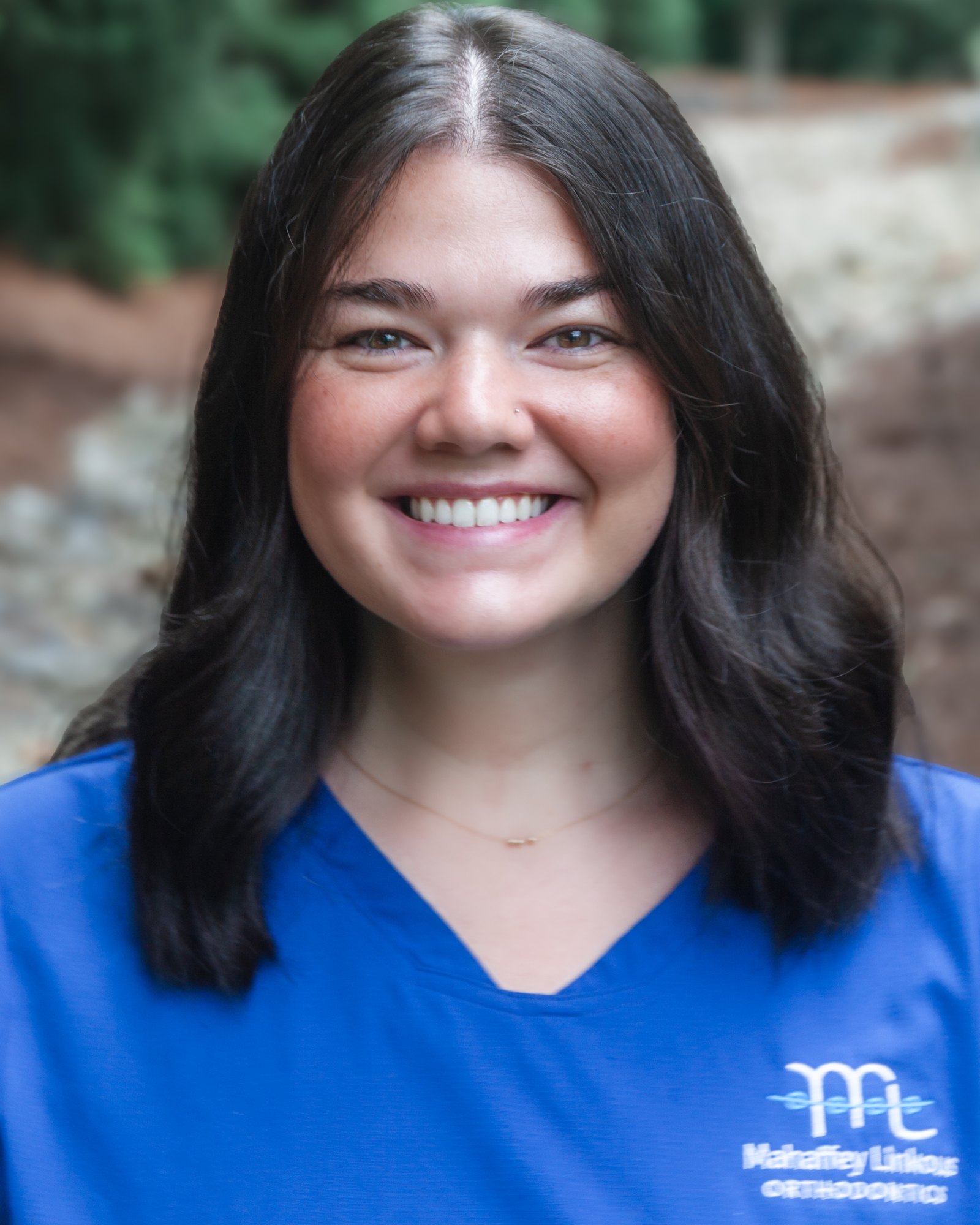 Sarah, Lab Assistant at Mahaffey Linkous Orthodontics, smiling outdoors in a branded blue polo