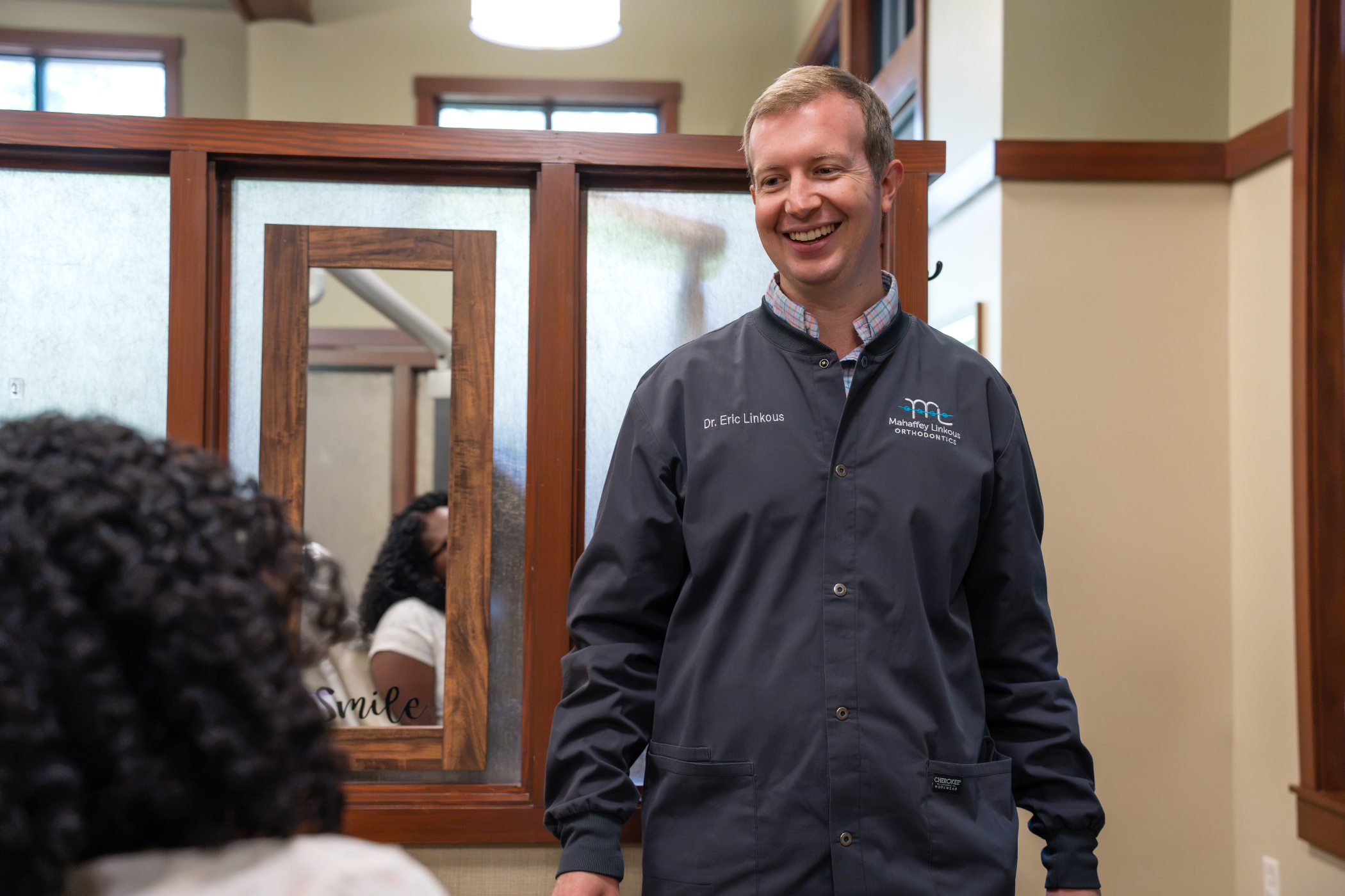 Dr. Eric Linkous, Peachtree City orthodontist at Mahaffey Linkous Orthodontics, smiling and greeting a patient in the treatment area of the Peachtree City, GA office